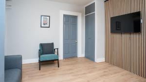 a living room with a blue door and a chair and a television at 1 BDR apartment at QUEENS UNI by Belfast City Breaks in Belfast