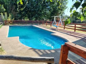 a swimming pool with a swing and a playground at Cabaña con jacuzzi, 7 personas. in Quillón