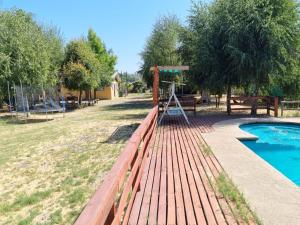a wooden fence next to a pool and a playground at Cabaña con jacuzzi, 7 personas. in Quillón