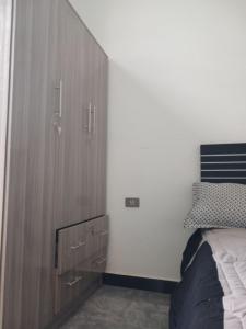 ein Schlafzimmer mit einem großen Holzschrank neben einem Bett in der Unterkunft Onset Apartment in Addis Abeba