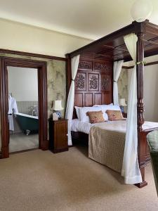 ein Schlafzimmer mit einem Himmelbett und einer Badewanne in der Unterkunft The Old Vicarage NI B&B in Ballywalter