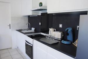 a kitchen with white cabinets and a black counter top at Ô P'tit Billard Baventais in Bavent