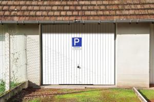a white garage door with a parking sign on it at Ô P'tit Billard Baventais in Bavent