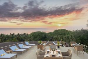 a view from the deck of a resort with chairs and tables at The Acacia Hotel & Spa in Candolim