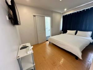 1 dormitorio con 1 cama blanca grande y TV en The Cute Silom hostel, en Bangkok