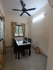 ein Esszimmer mit einem Tisch und einem Deckenventilator in der Unterkunft Lim Garden Homes in Balik Pulau