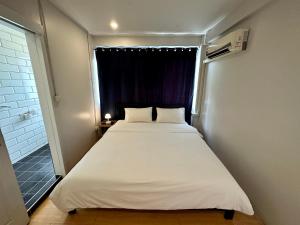 a bed in a small room with a window at The Cute Silom hostel in Bangkok