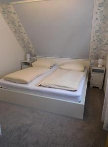 uma cama branca com duas almofadas em cima em Ferienwohnungen Ansbach - Ansbach Apartments - Your home away from home! em Ansbach