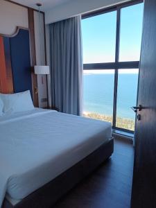 Ấp Thiẹn ÁiにあるApec Mandala Chambay Mui Ne Ocean viewのベッドと大きな窓が備わるホテルルームです。