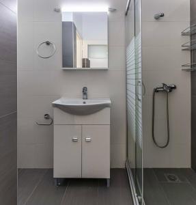 biała łazienka z umywalką i prysznicem w obiekcie Comfy Central Square Gem with Balcony w Kalamácie