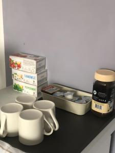 eine Küchentheke mit Tassen und einem Behälter mit Lebensmitteln in der Unterkunft Camelia Apartment with a breakfast in Subotica