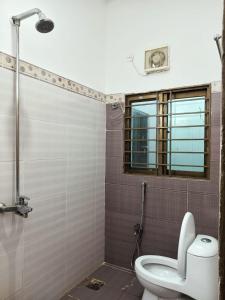 baño con aseo y ducha con ventana en Capital Guest Inn, en Rawalpindi