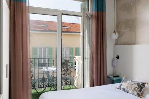 a bedroom with a bed and a large window with a balcony at Hôtel Byakko Nice in Nice +90 photos