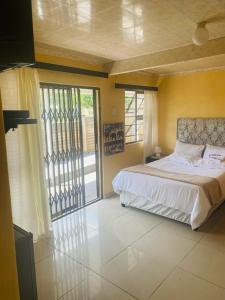 a bedroom with a bed and a sliding glass door at Eliza Guest House in Empangeni