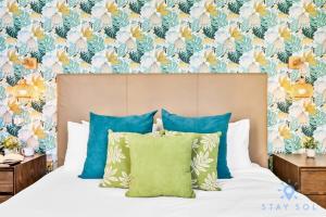a bedroom with a bed with blue pillows and a floral wallpaper at Costa Hollywood - Worth Traveling - Rooftop Pool- Gym in Hollywood