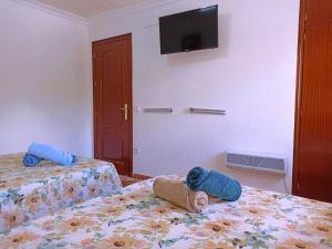 um quarto de hotel com duas camas e uma televisão na parede em El Azahar em Sevilha