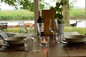 uma mesa com uma garrafa de vinho e copos em Vakantiehuis met omheinde tuin em Dokkum