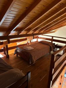 Cama en habitación con techo de madera en Cabañas Nevis, excelente ubicación en El Calafate