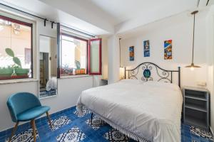 a bedroom with a bed and a chair and windows at Cascabella Taormina in Taormina