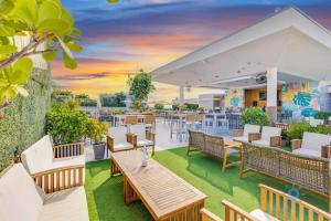 an outdoor patio with tables and chairs and a sunset at NEW!Beachfront Condo Resort- Balcony in Hollywood