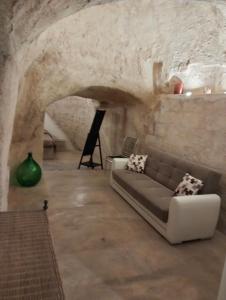 uma sala de estar com um sofá numa parede de pedra em Stone Rooms em Matera