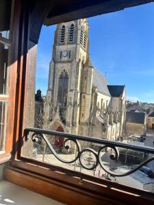 a window view of a church with a clock tower at Appartement neuf, centre-ville in Argenton-sur-Creuse