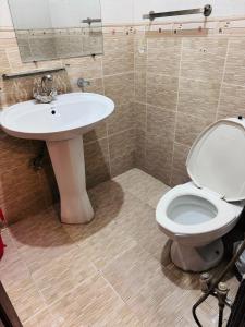 a bathroom with a white toilet and a sink at Madcrew Lodge in Islamabad