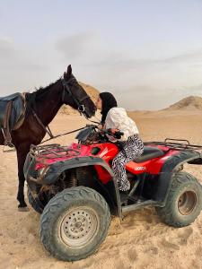 a person on a atv with a horse in the desert at 3-Cozy Bedroom Haven l Free Horseback Tours in Cairo