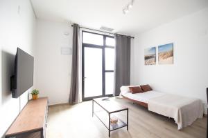 a white living room with a bed and a tv at Congresos Flat by Concept Flats in Valencia