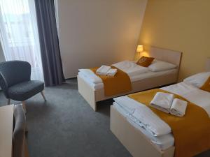 a hotel room with two beds and a chair at Hotel Eminent in Stupava