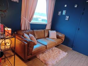 a brown leather couch in a living room with a window at Auberge La Péniche in Pierrefitte-sur-Loire