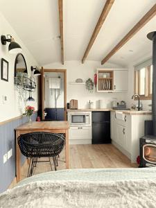 a kitchen with a table and a dining room at Hidden Gem Luxury Shepherd Hut - Pea Pod in Wimbish