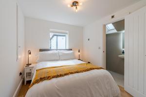 a white bedroom with a large bed and a window at Norton Coach House in Cheltenham