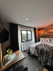 1 dormitorio con cama, mesa y ventana en Framptons Murzasichle Luxury Apartments tylko dla dorosłych, en Murzasichle