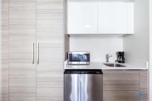 a kitchen with white cabinets and a stainless steel refrigerator at Amazing Pool - Gym - Hot Tub - Near Beach in Hollywood