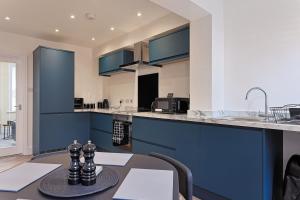 a kitchen with blue cabinets and a table at City Centre Riverside Retreat in Kent