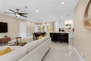 a white living room with a white couch and a kitchen at Just minutes driving to the Beach, Amazing Pool in Hallandale Beach