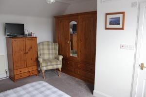 a bedroom with a cabinet and a chair and a television at Dunmhor Guest House in Kingussie