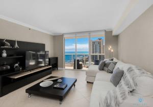 uma sala de estar com um sofá branco e uma televisão grande em Luxury Beachfront Resort, Amazing Views, Pools em Hallandale Beach