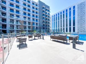 a patio with tables and chairs in front of a building at Stunning 1Bedroom with Balcony in Studio City in Dubai