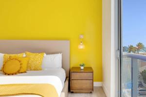 um quarto com paredes amarelas e uma cama com mesa de cabeceira em Lovely Apartment - Hollywood Beach - Rooftop Pool em Hollywood