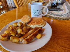 a plate of breakfast food with sausage potatoes and a cup at First Settlers Lodge in Weston