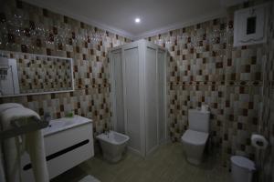 um banheiro com chuveiro, vaso sanitário e pia em Hôtel Mansour em Dakhla