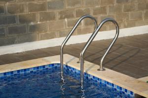 a swimming pool with two metal rails in the water at Green Villa - Ngôi Nhà Chung in Can Tho