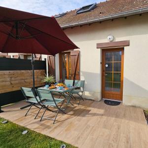 a patio with a table and chairs and an umbrella at Ô P'tit Billard Baventais in Bavent