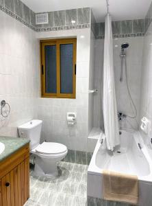 a bathroom with a toilet and a tub and a sink at City Center Apartments in Mellieħa