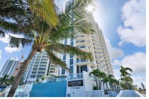 a tall building with a palm tree in front of it at New Sunny Isles Retreat: Oceanview Comfort in Aventura