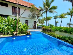 a swimming pool in front of a house with palm trees at Abogo Champa Villa Beach Da Nang in Da Nang