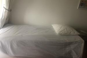 a white bed with a pillow on top of it at Nice studio near the sea "La brise marine" in Trouville-sur-Mer