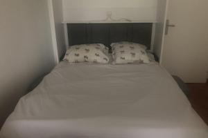 a bed with white sheets and pillows in a room at Nice studio near the sea "La brise marine" in Trouville-sur-Mer